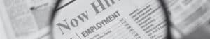 Magnifying glass hovering over the words now hiring in a job advertisement