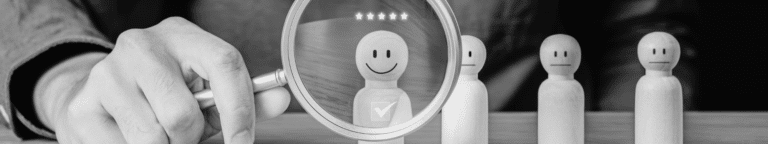 Hand holding magnifying glass over wooden figure that was chosen using recruitment strategies and tools